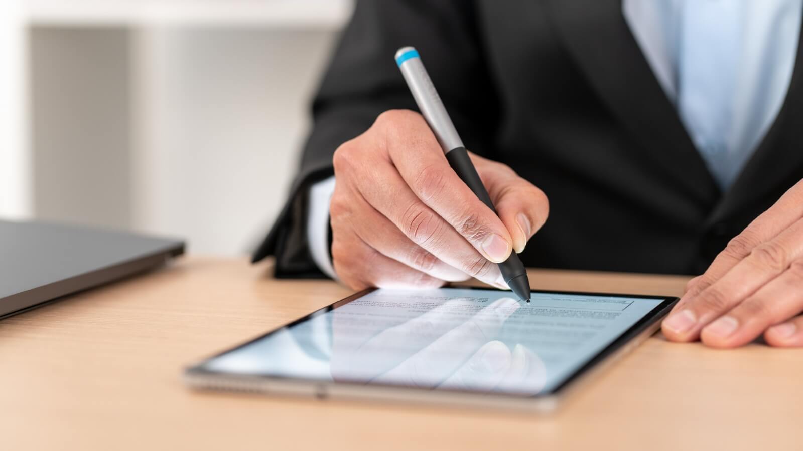 A woman holding a tablet uses the styles to sign a contract.