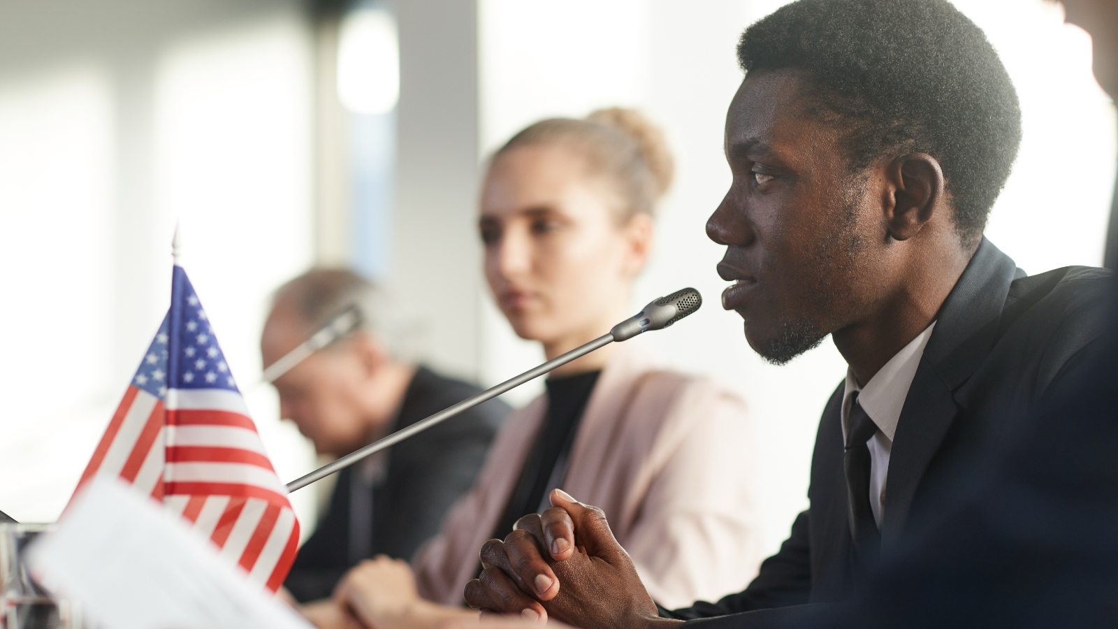 Three people discuss government policy at an official conference.